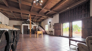 Una habitación amplia con techo de madera, una escalera y ventanas grandes.