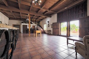 A spacious room with a wooden ceiling, a staircase, and large windows.