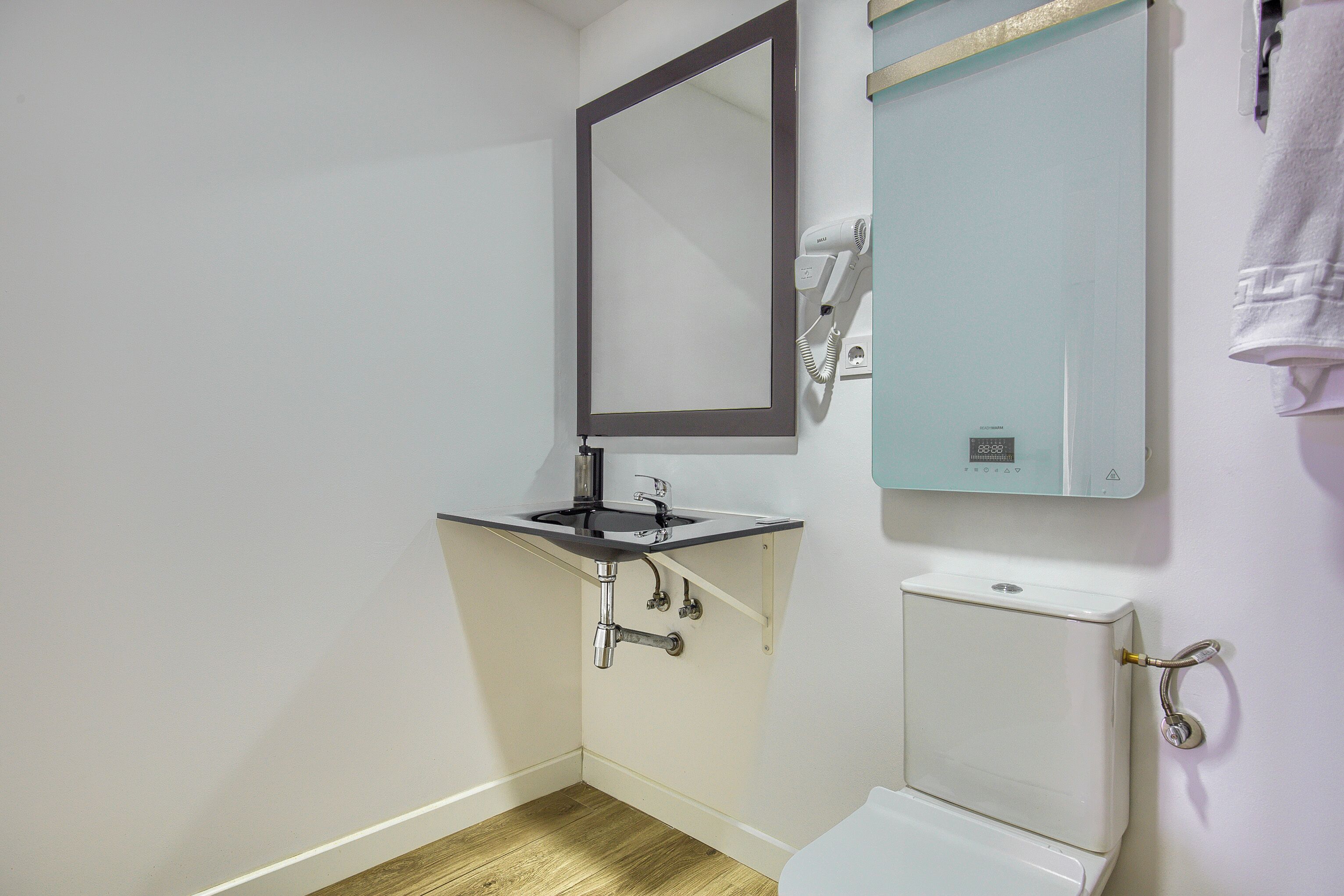 A small bathroom with a sink, mirror, and toilet.