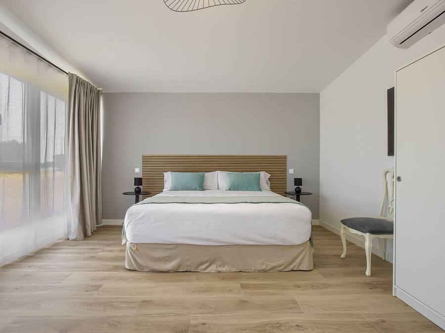Une chambre à coucher avec un lit, une chaise, une armoire et une fenêtre avec des rideaux.