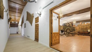 Un pasillo con piso de madera, una puerta de madera y una habitación con piso de madera y un carruaje.