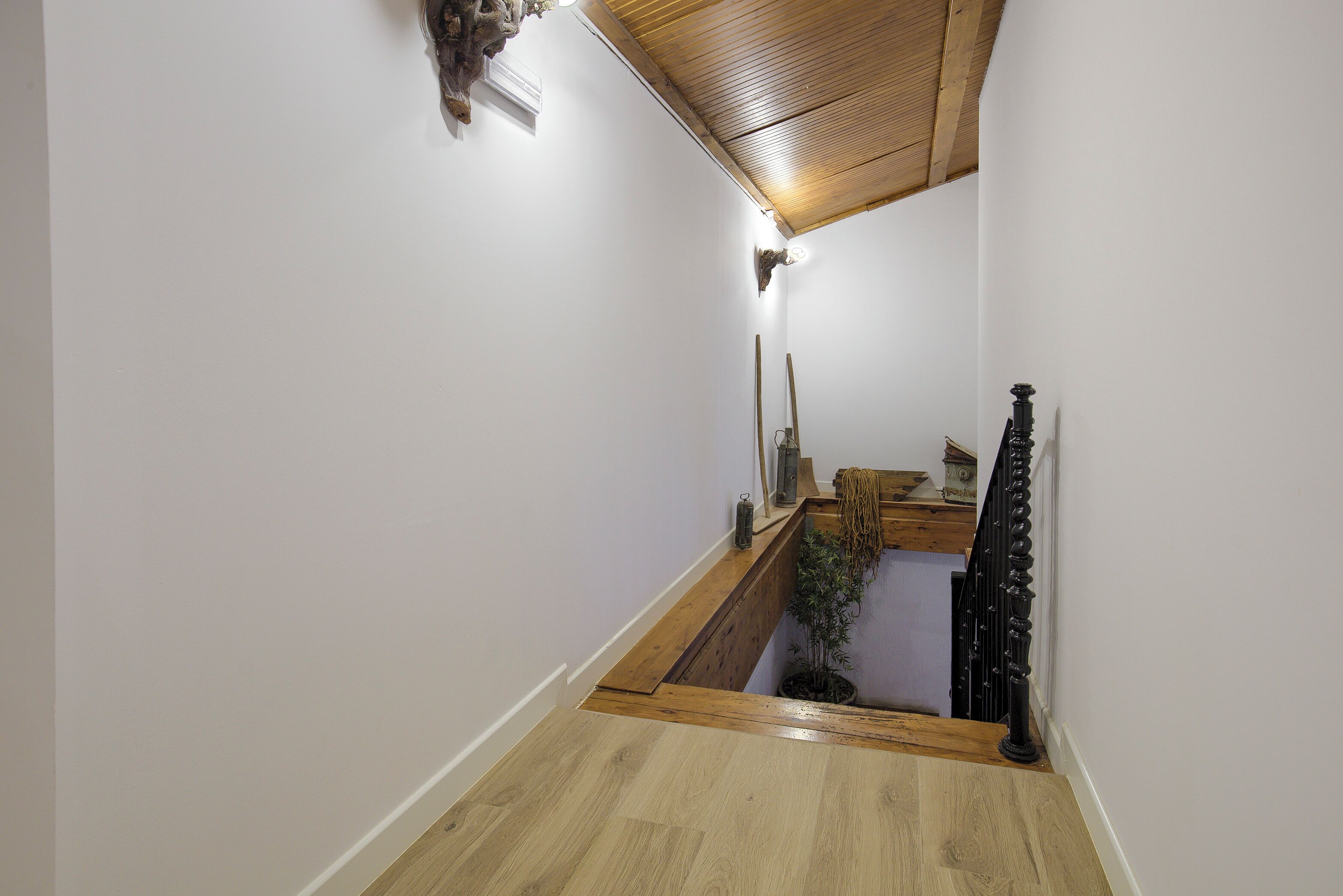 Una escalera estrecha con escalones de madera y barandilla negra.