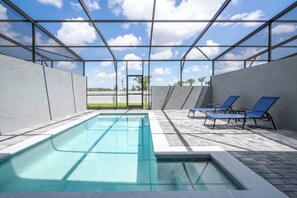 Une piscine dotée d’un toit en verre, entourée de chaises longues et offrant une vue sur des palmiers.