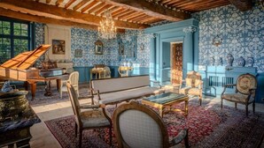 Una habitación con un piano de cola, sillones ornamentados, un sofá y una araña.