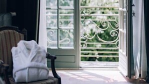 Una habitación con un ventanal grande, una silla con una toalla blanca y vistas a zonas verdes.