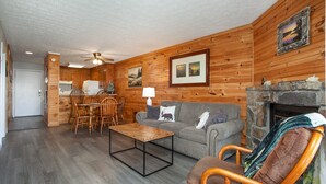 A cozy cabin interior with a dining area, a sofa, and a fireplace. - Stunning Mountain Views with Community Amenities! (Gatlinburg)