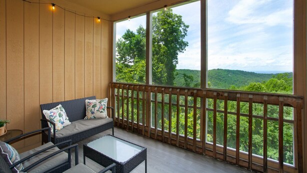A balcony with a wicker sofa and chairs, a glass table, and a wooden railing. - Stunning Mountain Views with Community Amenities! (Gatlinburg)