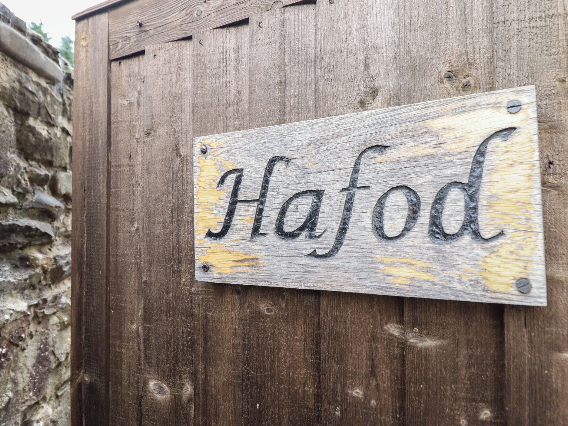 A wooden sign with the name "Hafod" mounted on a wooden fence.