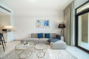 A modern living room with a sofa, ottoman, coffee table, and artwork on the wall.