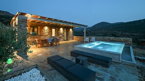 Una casa de piedra con piscina, mobiliario exterior y vistas a las colinas.