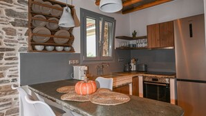 Una cocina con una isla de piedra, vigas de madera y una pared de piedra.