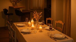 A dining table set for four with candles, a vase of dried flowers, and a hanging light fixture. - Gentle getaway near Beauval and the Châteaux (Romorantin-Lanthenay)