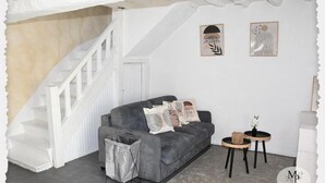 A modern living room with a grey sofa, white staircase, and two framed artworks on the wall. - Gentle getaway near Beauval and the Châteaux (Romorantin-Lanthenay)