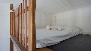 A single bed with white linens, a wooden headboard, and a small bedside table with a lamp.