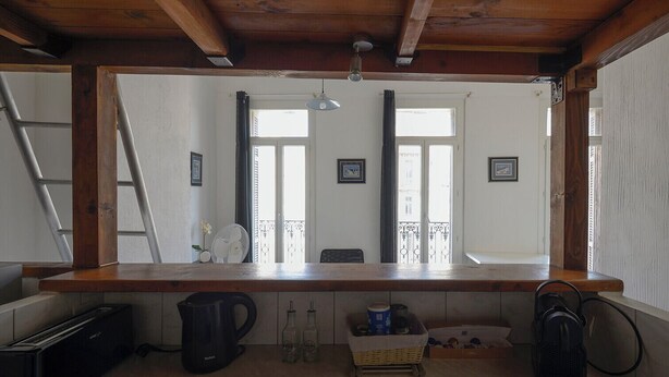 A kitchen with a wooden countertop, a kettle, a fan, and a basket.