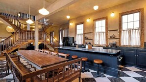 Un'ampia cucina con isola centrale, una zona pranzo con tavolo e panche in legno, e una scala che conduce a un livello superiore.