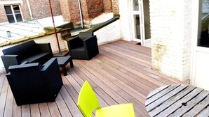 An outdoor patio with wooden flooring, black and yellow chairs, and a table. - Lille Avenue, Conviviality, Comfort (Lille)