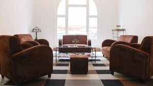 A room with a checkered floor, a central coffee table, and four brown leather armchairs. - Lille Avenue, Conviviality, Comfort (Lille)