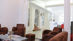 A spacious living area with leather armchairs, a coffee table, and a staircase leading to a dining area. - Lille Avenue, Conviviality, Comfort (Lille)