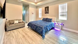 Une chambre à coucher comprenant un lit, un canapé, un ventilateur de plafond et une table de chevet avec une lampe.