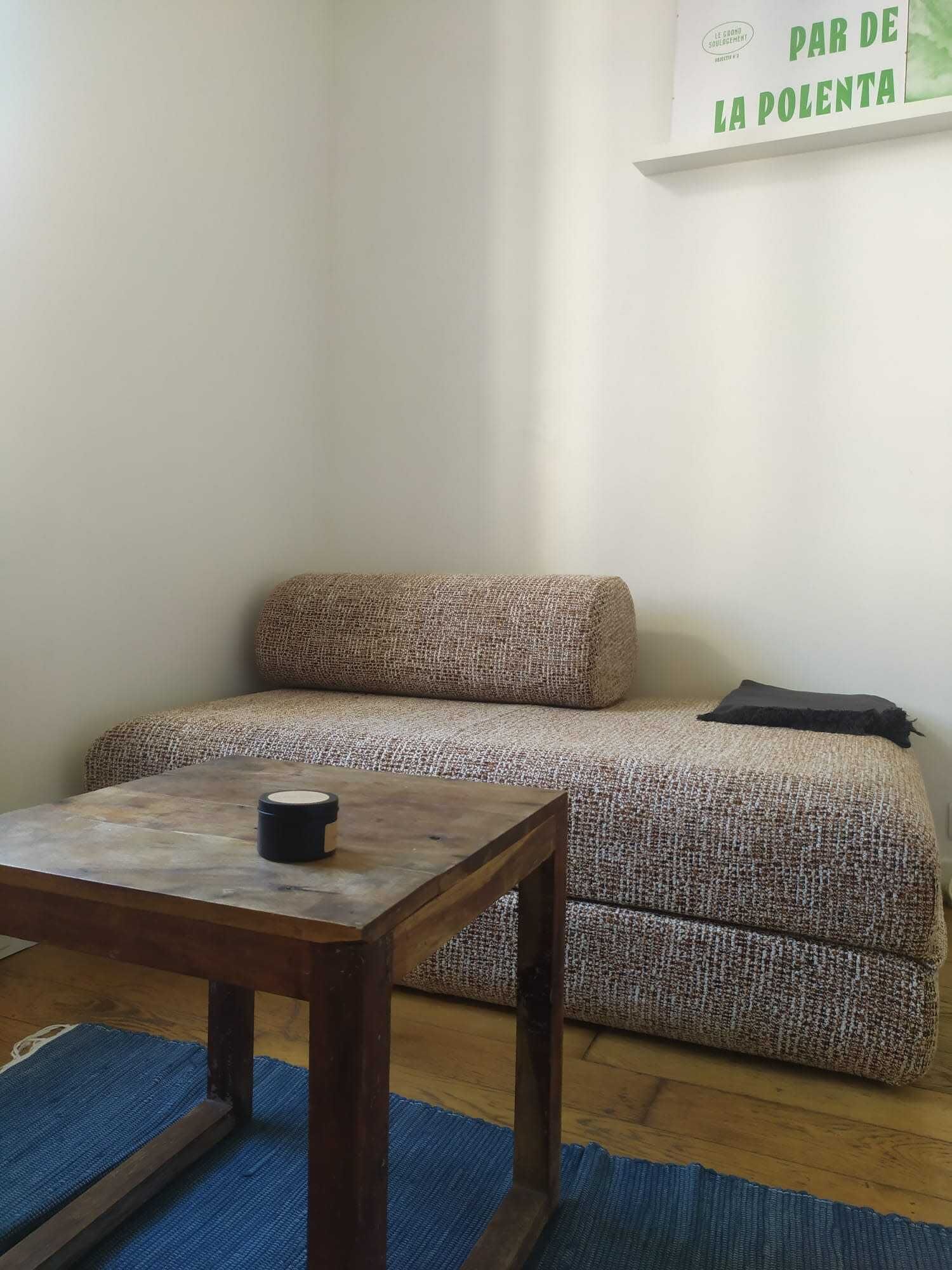 Une pièce avec un canapé, une petite table en bois et un tapis bleu.