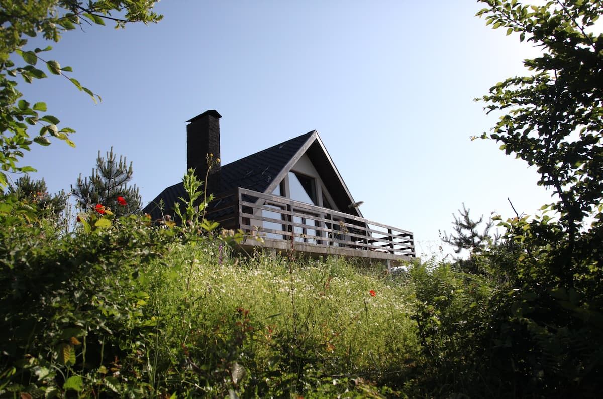 A cabin with a sloped roof, a chimney, and a balcony.