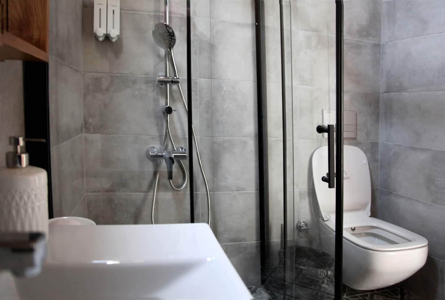 A modern bathroom with a glass-enclosed shower, a white toilet, and a white sink.