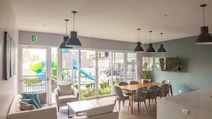 A modern kitchen with a dining area, large windows, and a view of a playground. - Luxury Skyline City View KING Bed FREE Pool & Gym (Ciudad de Guatemala)