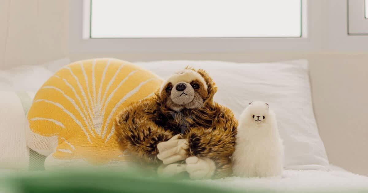 A bed with a plush toy bear and a white stuffed animal.