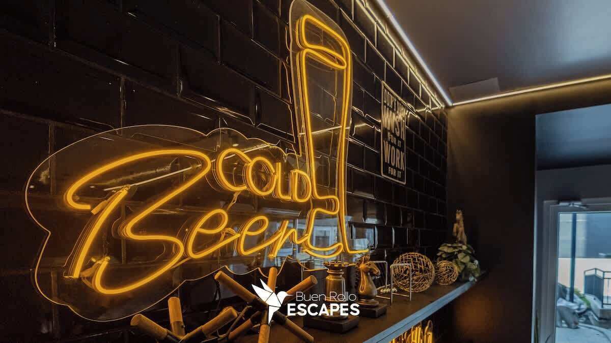 A neon sign reading "Cold Beer" in a modern bar setting with a brick wall and various bar items on display.