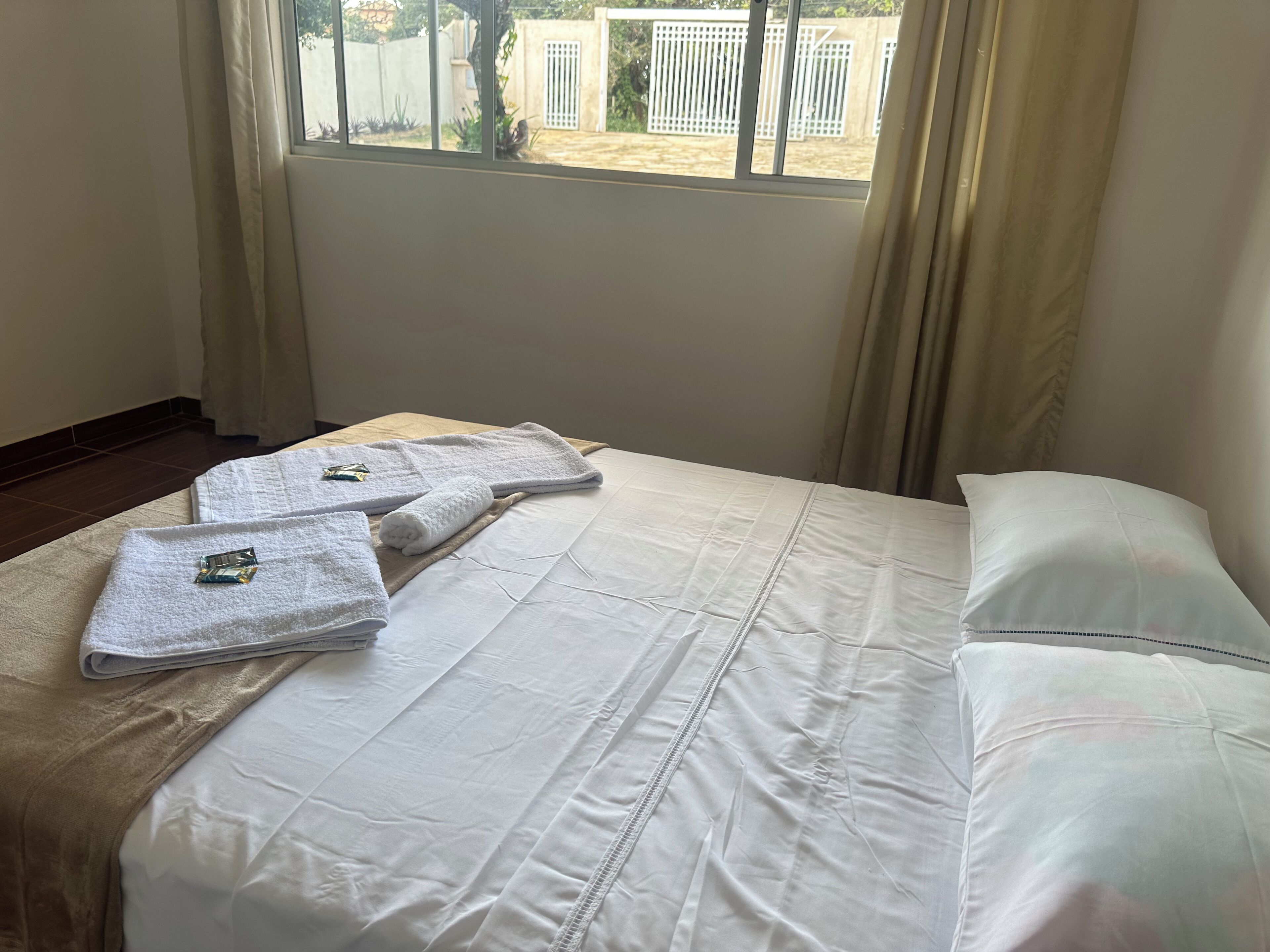 Une chambre d’hôtel avec un lit, du linge de lit blanc, une fenêtre avec des rideaux et une vue sur l’extérieur.