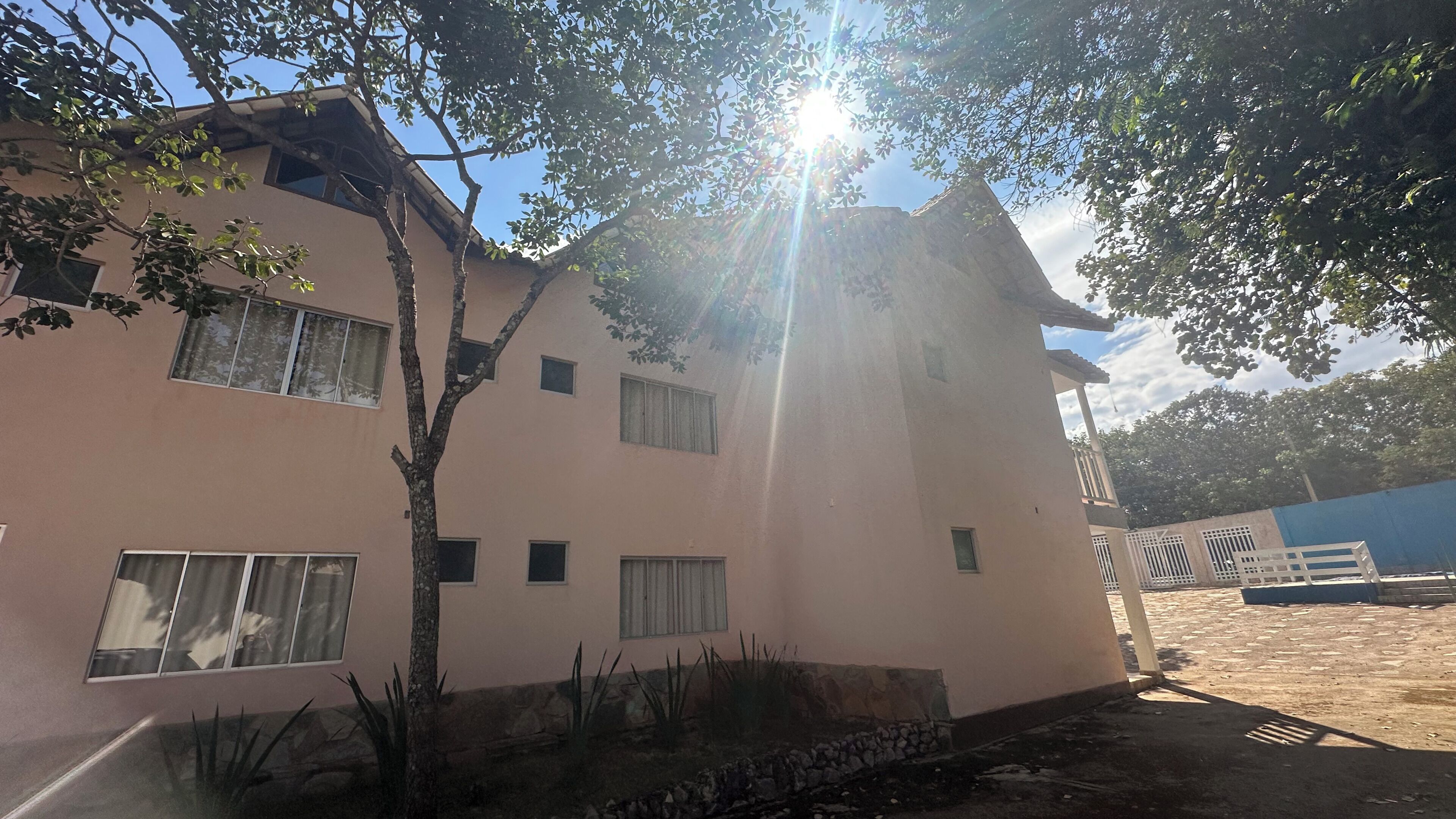 Un edificio de varios pisos con fachada rosa, numerosas ventanas y un árbol en la parte delantera.