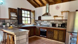 Una cocina con una isla grande, armarios de madera, horno empotrado y campana extractora de acero inoxidable.