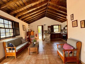 A spacious living area with a high wooden ceiling, a sofa, a coffee table, and a kitchen in the background. - Holiday Home 'Casa Castro' with Mountain Views, Private Pool and Wi-Fi (Los Llanos de Aridane)