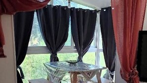 A dining area with a glass table and chairs, curtains, and a view of greenery outside. - Little corner of Paradise (Yssingeaux)