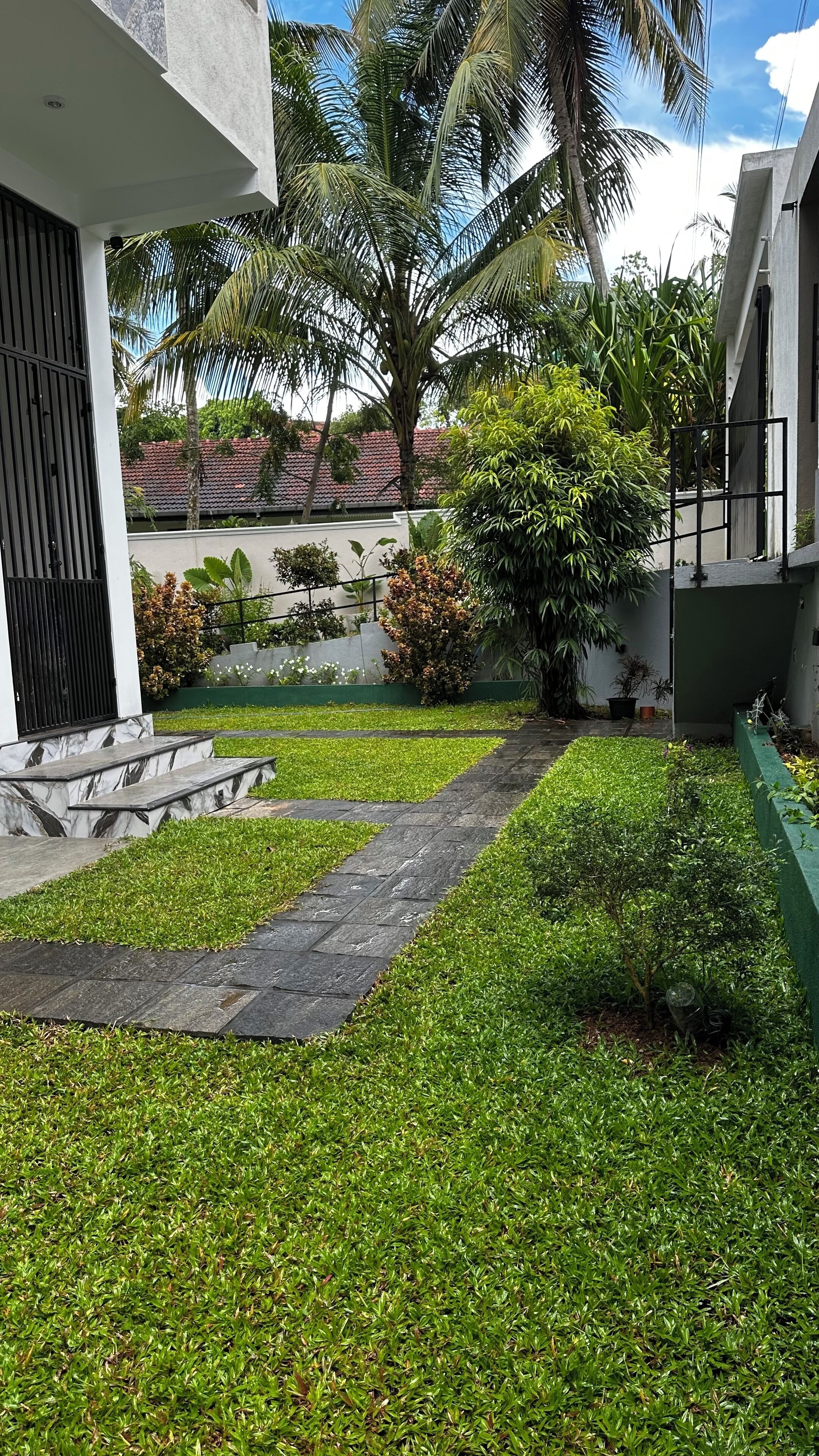 A well-maintained garden with a stone pathway leading to a building entrance.