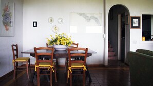 A dining area with a wooden table and chairs, a vase with yellow flowers, and a framed picture on the wall. - Villa Rosa in Marina di Maratea (Marina)
