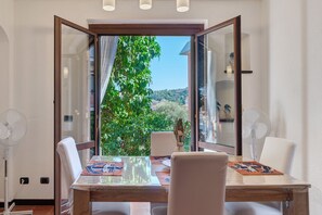 A dining area with a table, chairs, and a view of greenery through an open door. - Apartment 'Casa Sole e Mare' with Shared Pool and Private Garden (Arenzano)