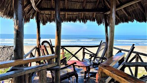 A wooden deck with chairs overlooking a beach and ocean.