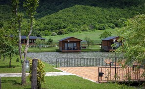 A lakeside resort with wooden cabins, a wooden deck, and a metal fence.
