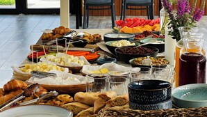 Ein reichhaltiges Frühstücksbuffet mit verschiedenen Speisen und Blick auf einen See durch große Fenster.