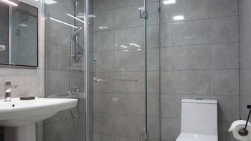 Une salle de bain moderne avec une douche à parois de verre, un lavabo blanc et des toilettes.