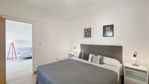 Un dormitorio moderno con una cama grande, mesitas de noche y vistas a un balcón.