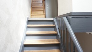 A staircase with wooden steps and a metal handrail, leading to a white door at the top. - Modern apt | old building I near the Rhine| view of the fortress | SmartTV (Koblenz)