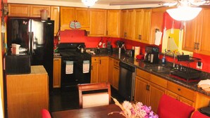 Una cocina con armarios de madera, un refrigerador negro, una estufa y un fregadero.