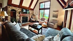A cozy living room with a stone fireplace, wooden beams, and comfortable seating. - Foxwood at Snowshoe Mountain (Snowshoe)