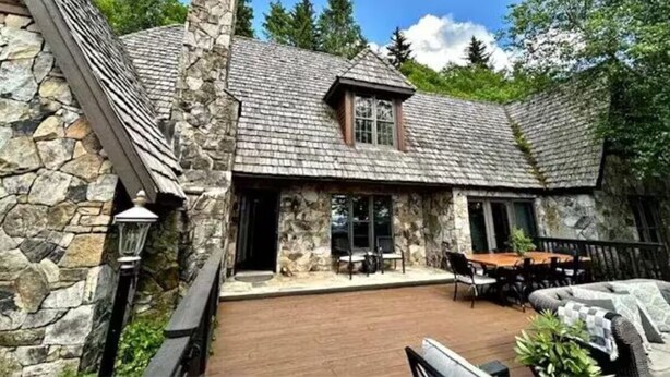 A stone house with a wooden deck, a dining area, and a large window. - Foxwood at Snowshoe Mountain (Snowshoe)