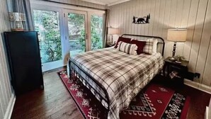 A bedroom with a bed, a nightstand, a lamp, a dresser, and a sliding glass door leading to a balcony. - Foxwood at Snowshoe Mountain (Snowshoe)