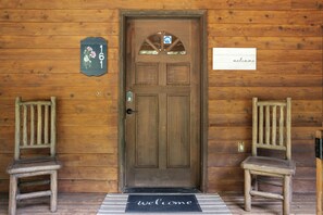 A wooden door with a number plaque, a welcome sign, and a doormat.