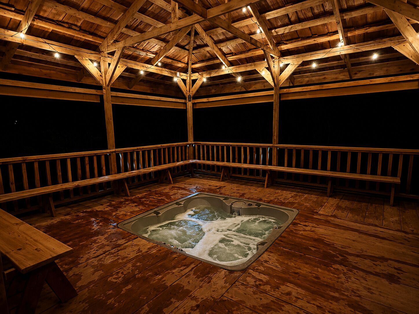 A wooden deck with a hot tub, wooden railings, and a wooden ceiling structure.